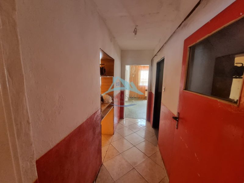 Egy családi ház folyosója csempézett padlóval és piros ajtókkal.