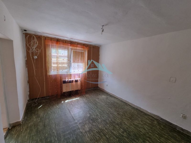 Szoba egy családi házban padlóval és függönyös ablakokkal.