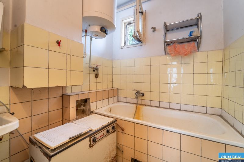 Fürdőszoba egy családi házban csempékkel és káddal, régi bojlerrel felszerelve.