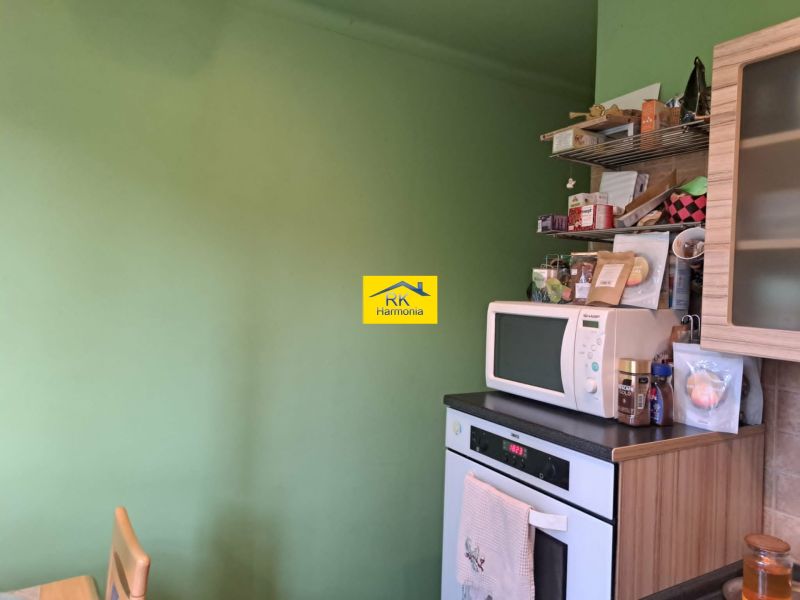 Konyha egy kétszobás lakásban mikrohullámú sütővel és nyitott polcokkal.