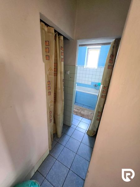 Fürdőszoba egy családi házban kék káddal és függönyökkel, csempézett padlóval.