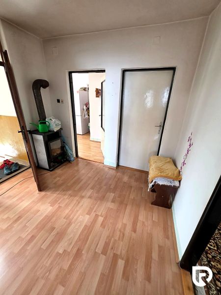 Családi ház belső tere fa dekorációjú padlóval, kandallóval és más helyiségekbe vezető ajtókkal.
