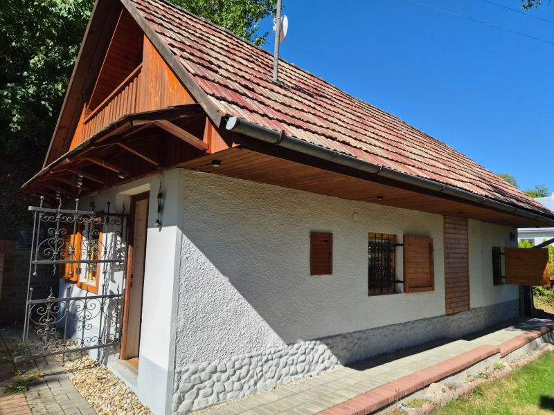 Családi ház Mikušovcén fa zsalugáterekkel és piros tetővel, zölddel körülvéve.
