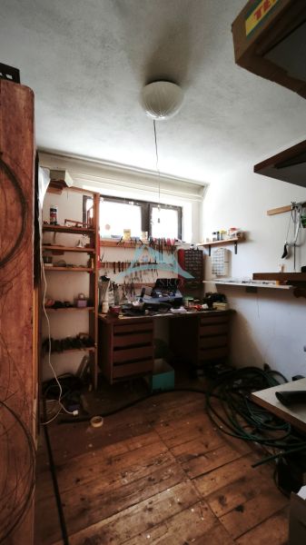 Műhely polcokkal és faasztallal egy családi házban, fa dekoros padlóval.