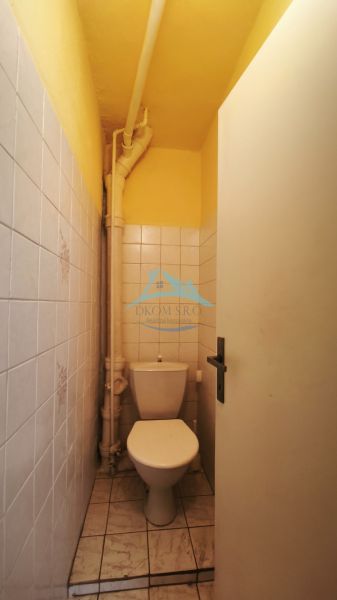 Kis, keskeny WC csempével a családi házban fehér csempékkel.