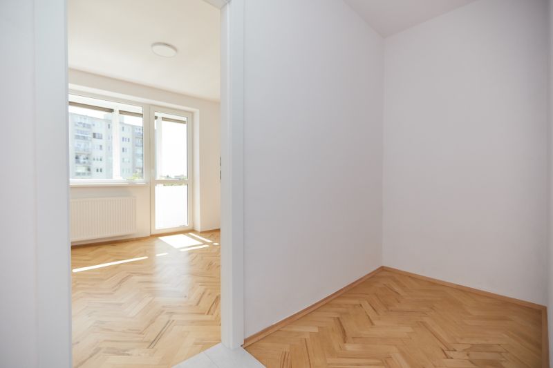 Világos szoba egy háromszobás lakásban, fa dekorációjú padlóval és nagy ablakkal.