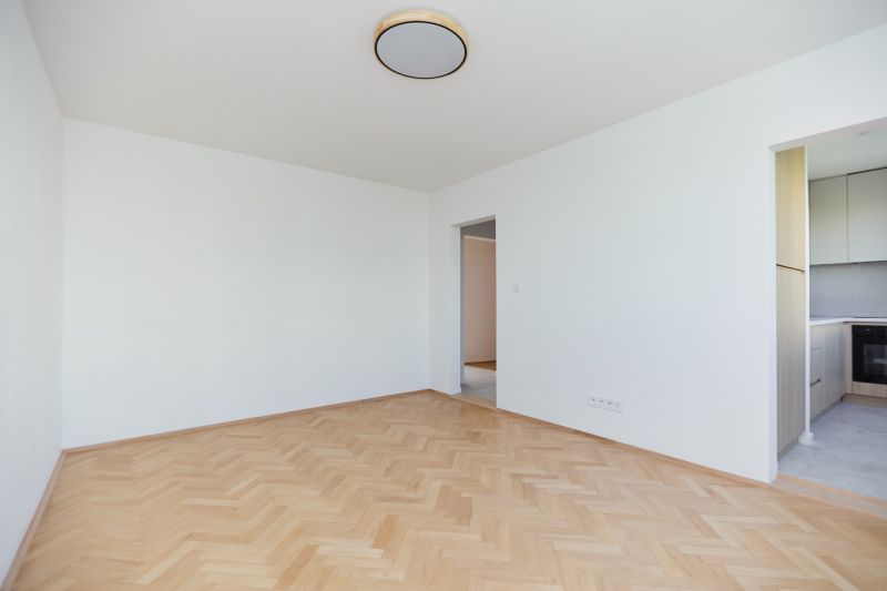 Üres szoba fa dekor padlóval és kilátással a konyhára egy háromszobás lakásban.
