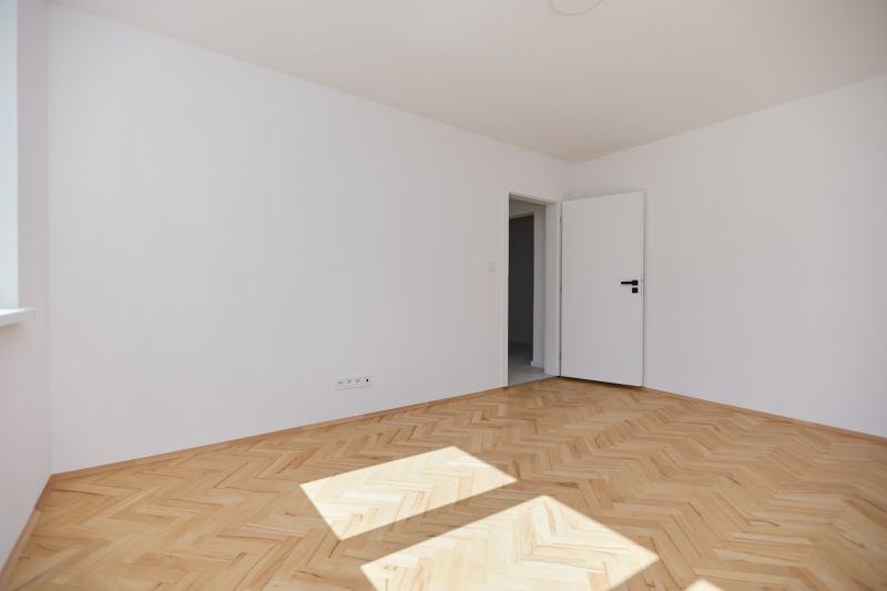 Világos szoba fehér falakkal és fa dekorációjú padlóval, 3 szobás lakás.