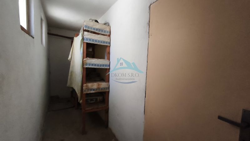 Keskeny folyosó polcokkal egy családi házban, egyszerű berendezés.