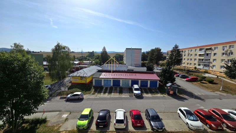 Kilátás a Besztercebányai Német útra épületekkel és parkolóval.