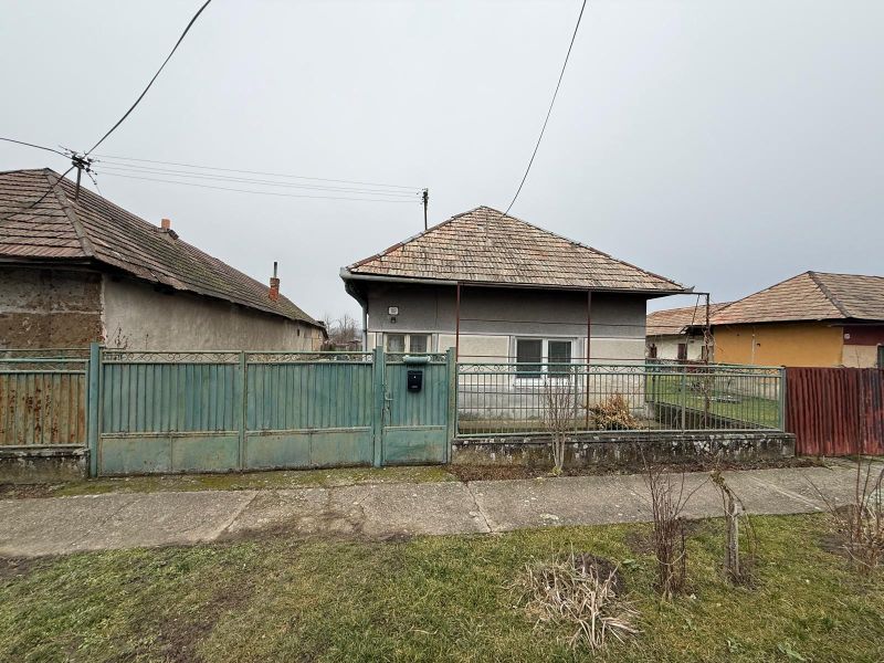 Családi ház Sikenicén fém kerítéssel és ferde tetővel.