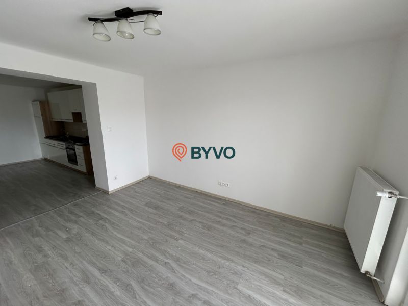Háromszobás lakás nappalija fa dekor padlóval és bal oldalon konyhával.
