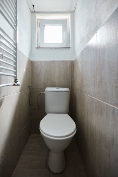 Fürdőszoba a házikóban WC-vel és világos árnyalatú burkolattal.