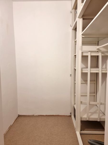 Tárolóhely fehér polcokkal egy kétszobás lakásban, szőnyeggel borított padlóval.