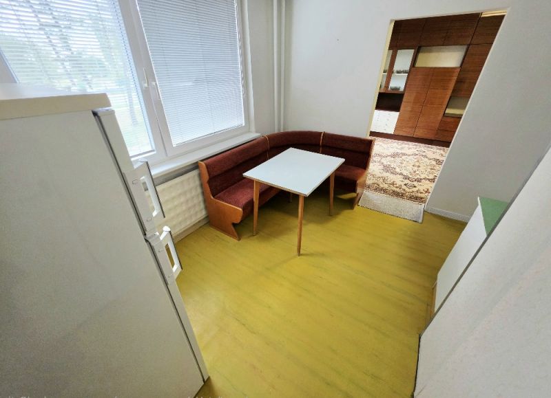 Konyha háromszobás lakásban sarokpadkával és asztallal.