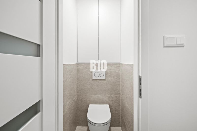 Fehér ajtós és csempés WC egy háromszobás lakásban.