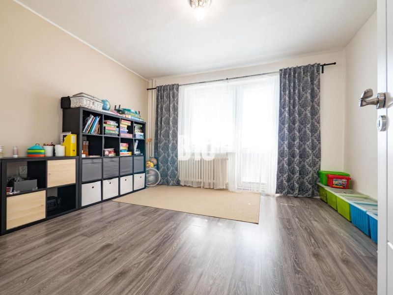 Szoba egy családi házban, fa dekoros padlóval, polccal és játékokkal.