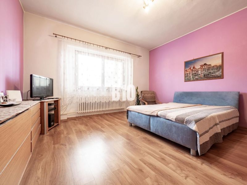 Hálószoba egy családi házban, fa dekorációjú padlóval, bútorokkal és televízióval.
