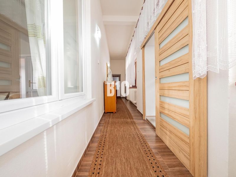 Folyosó egy családi házban fa dekoros padlóval és tolóajtókkal.
