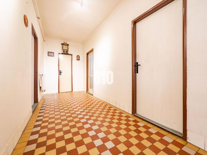 Családi ház folyosója csempézett padlóval és fehér falakkal.