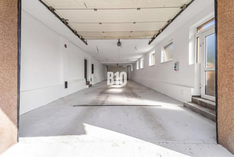 Tágas garázs egy családi házban, Nitra városában, több ablakkal és fehér falakkal.