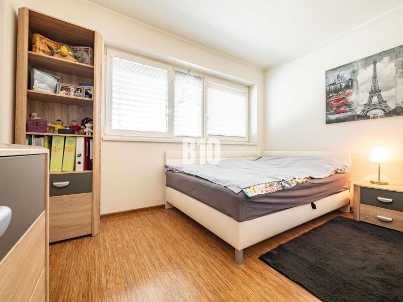 Hálószoba egy családi házban, fa dekoros padlóval és könyvekkel, valamint játékokkal teli polccal.