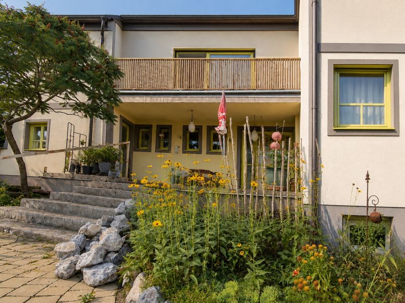 Családi ház Podersdorf am See-ben kőlépcsőkkel és virágokkal teli kerttel.
