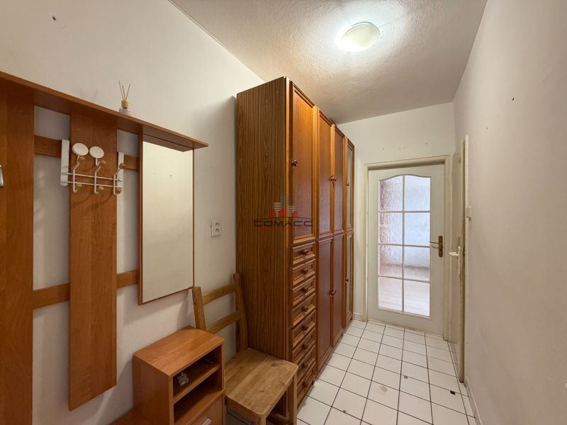 Folyosó egy 3 szobás lakásban fa dekorációval és járólappal a padlón.