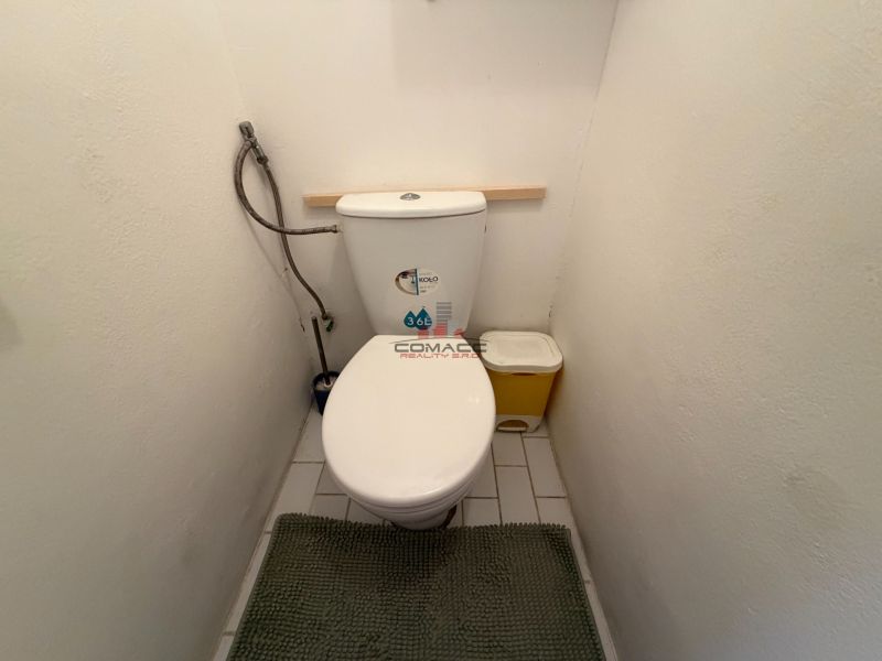 A fehér falakkal és csempékkel rendelkező háromszobás lakás WC-je.