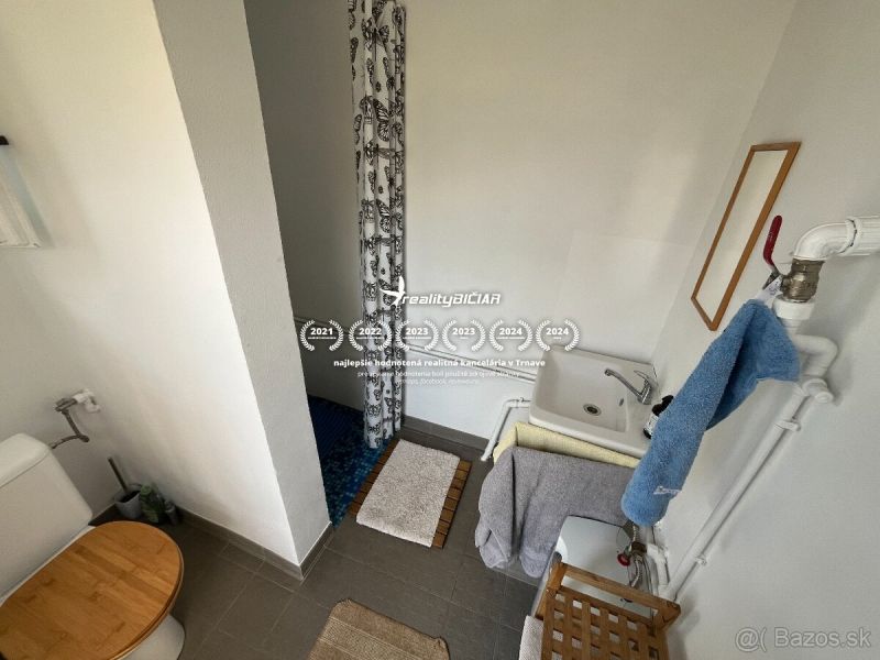 Fürdőszoba WC-vel, mosdóval és zuhanyzóval egy egyszerűen kialakított faházban.