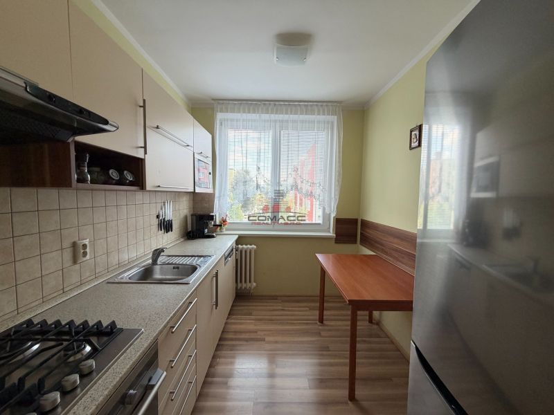 Konyha egy háromszobás lakásban fa dekor padlóval és konyhabútorral.