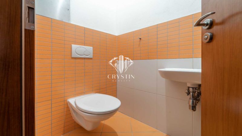 Fürdőszoba a nyaraló apartmanban narancssárga csempékkel és fali WC-vel.