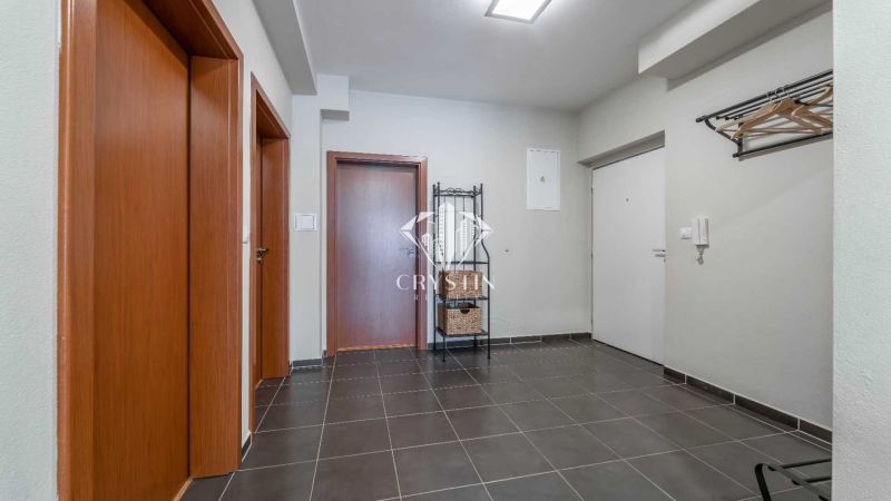 A nyaraló apartman előcsarnoka sötét padlólappal, faajtókkal és fogassal.