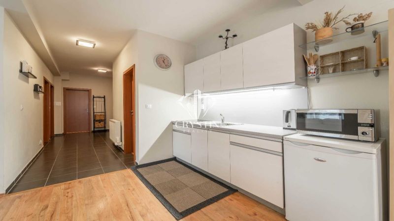 Konyhasarok konyhapulttal és mikrohullámú sütővel, fa hatású padlóval egy üdülő apartmanban.