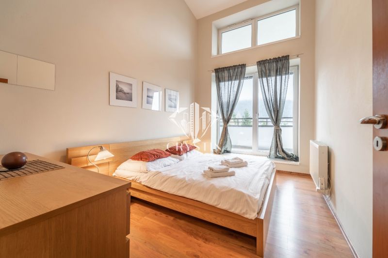 Világos hálószoba franciaággyal és fa dekorációjú padlóval egy nyaraló apartmanban.