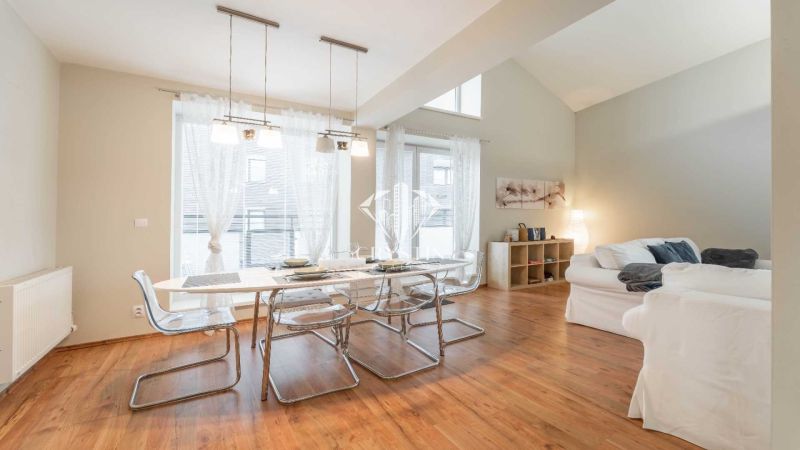 Rekreációs apartman étkezőasztallal, kényelmes kanapékkal és fa dekorációjú padlóval.
