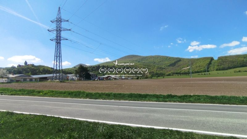 Táj a Smolenice-i Továrenská utcában mezőgazdasági és erdőterületekkel, valamint elektromos vezetékkel.