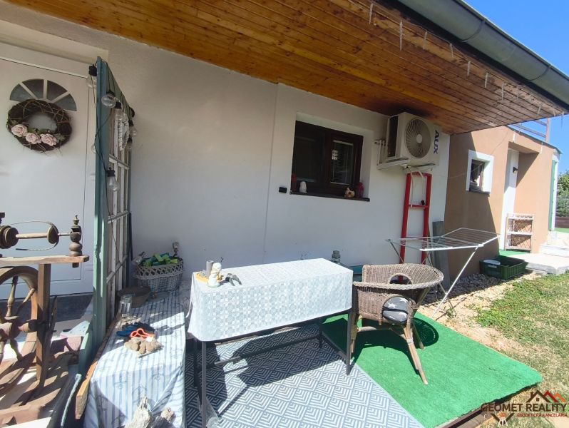 Egy családi ház terasza Divínben baldachinnal, asztallal és rattan székkel.