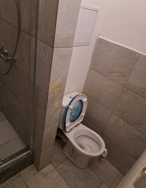 Fürdőszoba WC-vel és zuhanyzóval a garzonlakásban.