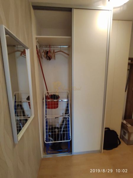 Beépített szekrény tolóajtókkal, akasztókkal és tükörrel egy kétszobás lakásban.
