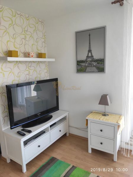 Nappali egy kétszobás lakásban világos bútorokkal és Eiffel-torony dekorációval.
