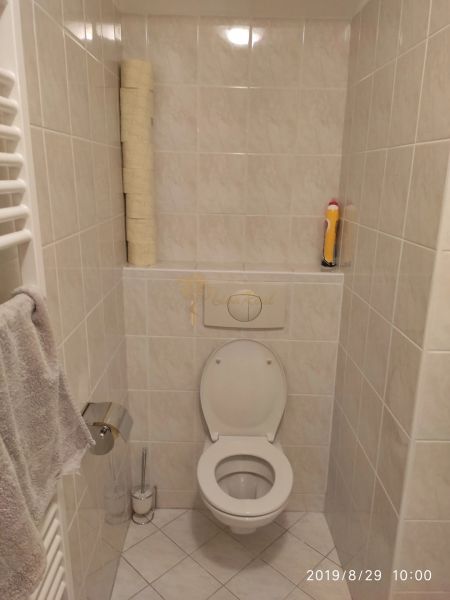 Fürdőszoba WC-vel, papírtartóval és törölközőtartóval egy kétszobás lakásban.