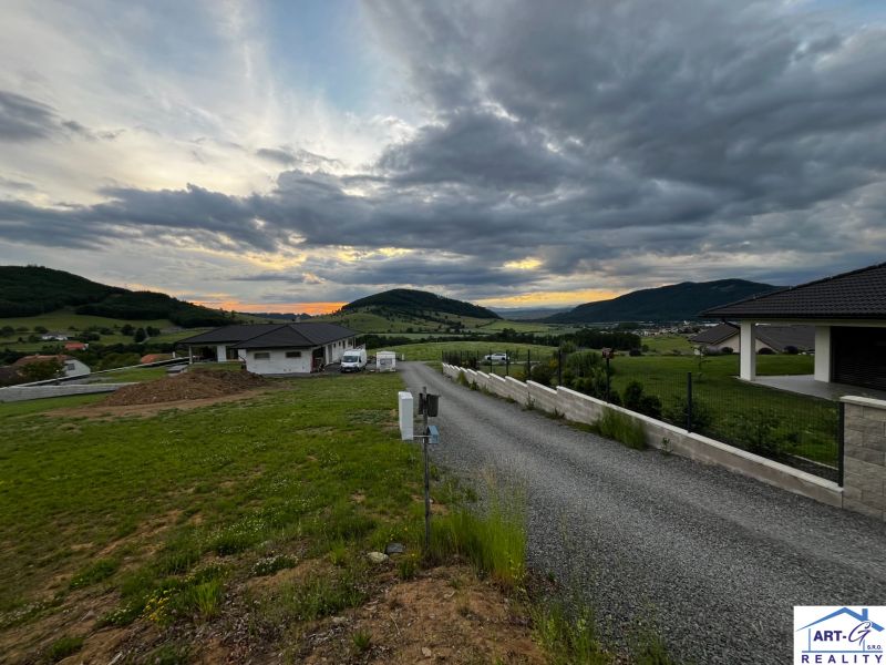 Stožok község panorámája naplementével és lakóterületekkel a dombos vidéken.