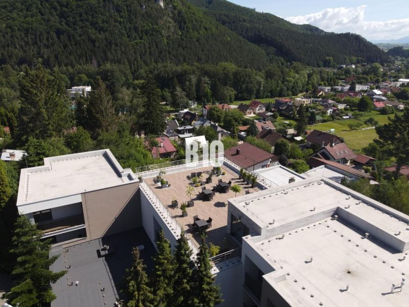 Kilátás egy tetőteraszra az épületek között, amelyeket természet vesz körül Rajecké Teplicében, az M. R. Štefánika utcában.