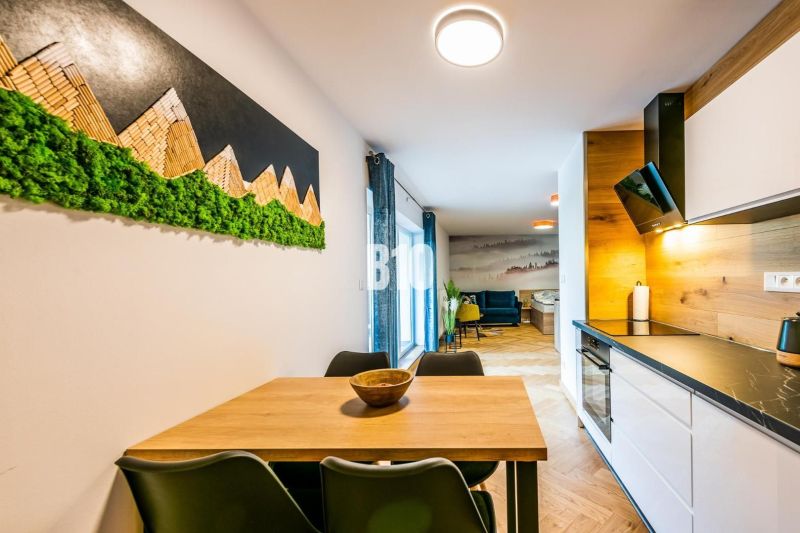Nyaraló apartman belső tere konyhával és asztallal, fa dekoros padlóval.