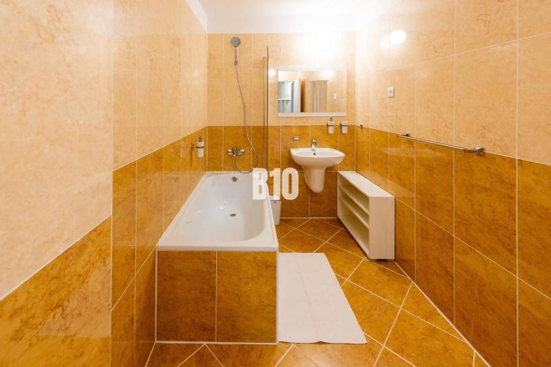 Fürdőszoba a nyaraló apartmanban káddal, mosdóval és világos csempékkel.