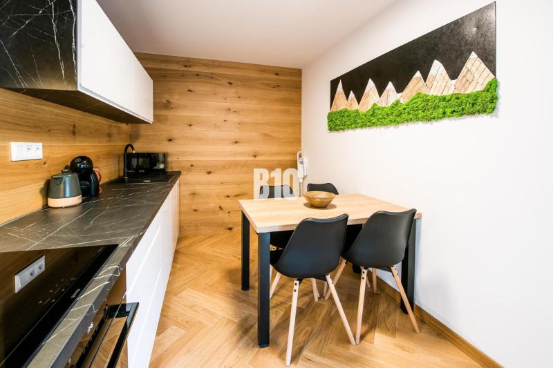 Nyaraló apartman belső tere konyhával, étkezőasztallal és fa dekorációjú padlóval.