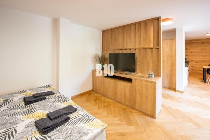 Rekreációs apartman ággyal, TV-vel, fa dekoros padlóval és fa bútorokkal.
