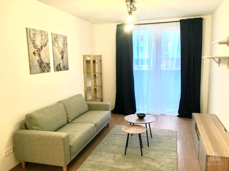 Nappali egy kétszobás lakásban kanapéval és asztalokkal fa dekor padlón.