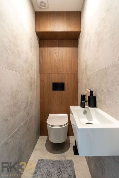Fürdőszoba fa mintás padlóval és fehér fali WC-vel egy kétszobás lakásban.